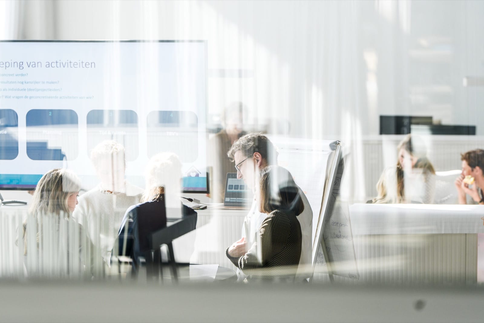 Professionals in een werkoverleg, met op het scherm de groepering van activiteiten