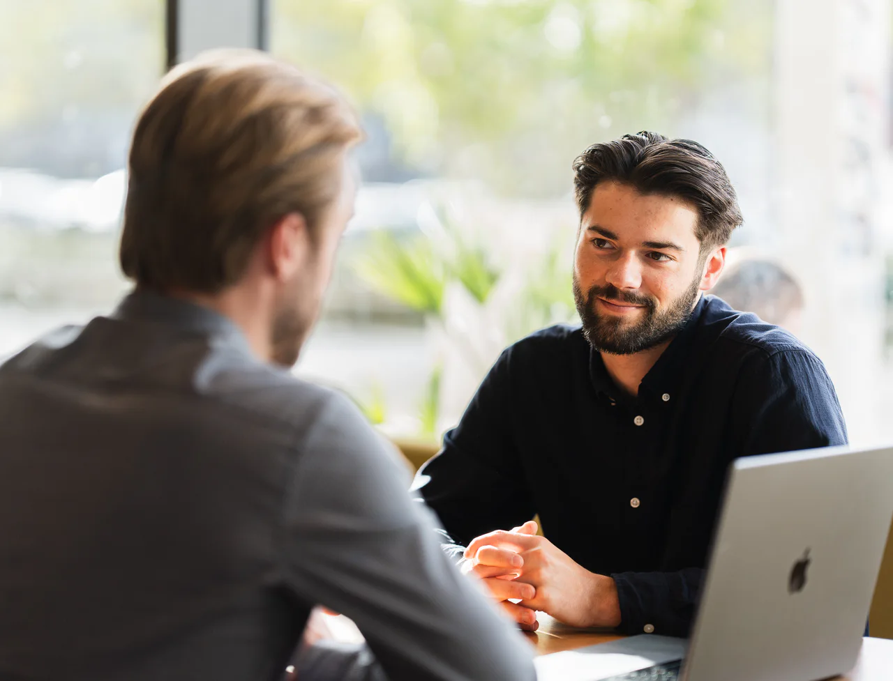 Twee collega’s in gesprek aan tafel bij het raam