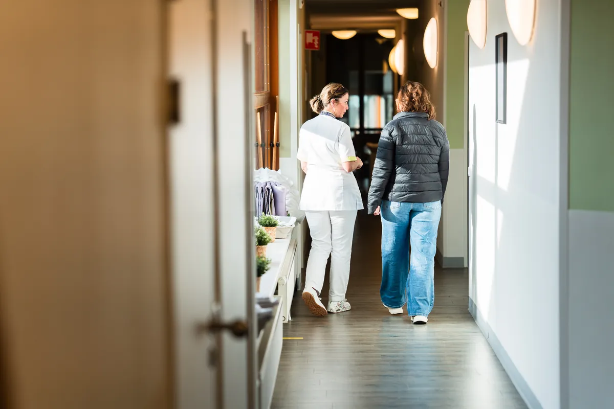Een student en een begeleider lopen samen door de gang