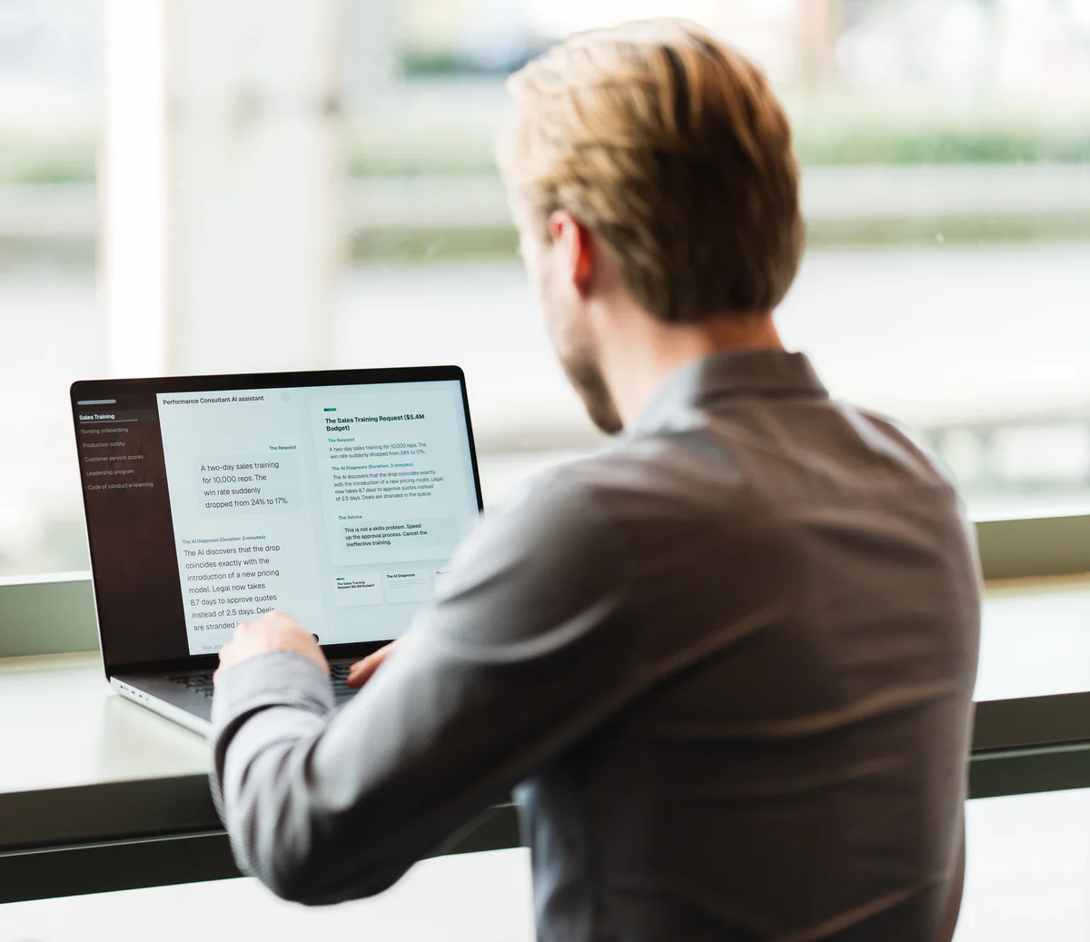 Een L&D-adviseur aan zijn laptop bij het raam, met de Performance Consultant AI open